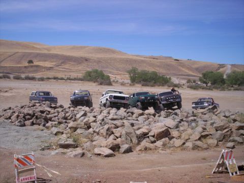 1989 Ford Bronco - Multiple off-road vehicles traverse a challenging rock formation on a sunny day.