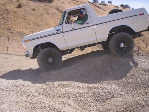 1989 Ford Bronco - A man drives a white Ford Bronco up a steep, rocky incline on a sunny day.