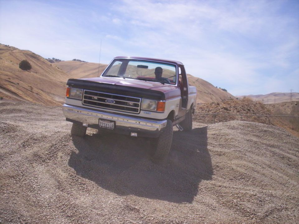 1987 Ford F-150 pickup truck with two-tone paint, parked on a gravel hill