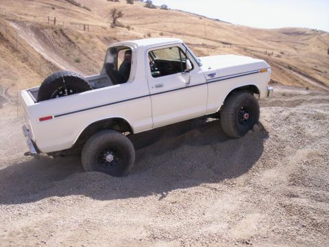 1989 Ford Bronco - White Ford Bronco navigating rough terrain on a sunny day.
