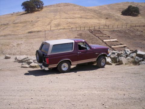 1989 Ford Bronco - This Ford Bronco is parked on a dirt road with a dry, hilly landscape behind it.