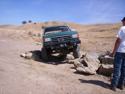 1989 Ford Bronco - A green 1987 Ford F-Series truck is shown navigating a rocky trail, demonstrating its off-road capabilities.