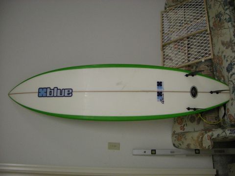 1995 Ford Bronco - A white surfboard with green rails and a blue 'Xblue' logo is mounted on a wall.