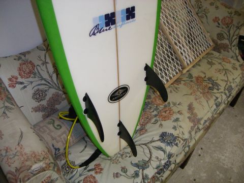 1995 Ford Bronco - A surfboard with 'Blue Surfboards' branding is propped up on a couch.