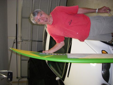 1995 Ford Bronco - A man poses with a surfboard, with a white vehicle partially visible behind him.