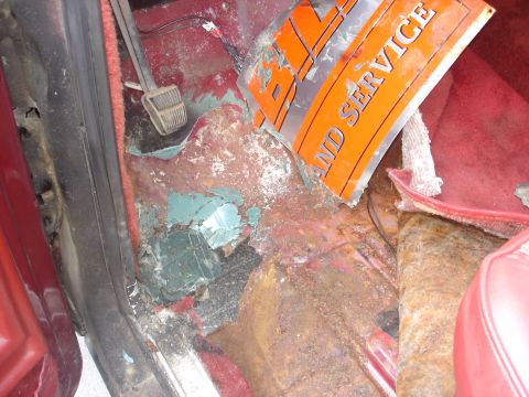 1979 Ford Bronco - The interior floor shows significant rust and damage, with a partial orange sign visible.