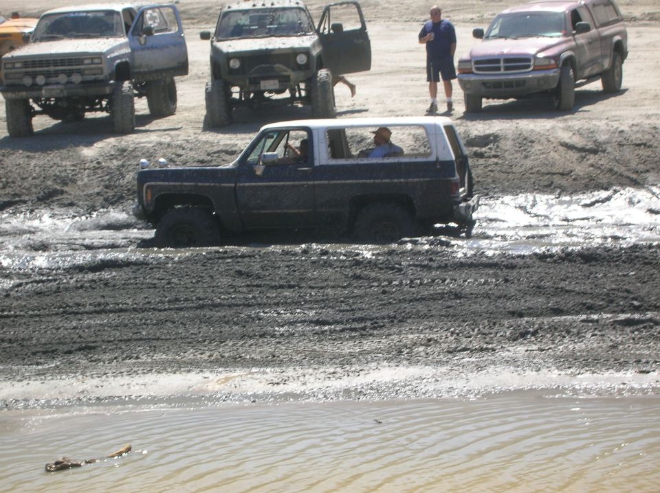 Dark blue and white SUV stuck in mud, 3/4 front view