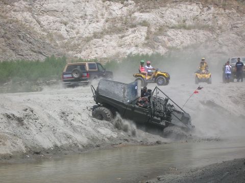 1985 Ford Bronco - A 1985 Ford Bronco navigates a dusty off-road course alongside other vehicles and ATVs.
