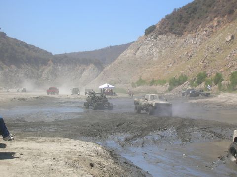 1985 Ford Bronco - Multiple trucks are engaged in mud bogging activities in a dusty, outdoor environment.