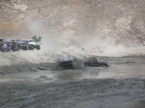1985 Ford Bronco - Off-road vehicles tackle a challenging mud pit during an event.