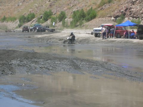 1985 Ford Bronco - People and vehicles gather at a muddy area, with an ATV navigating through the mire.