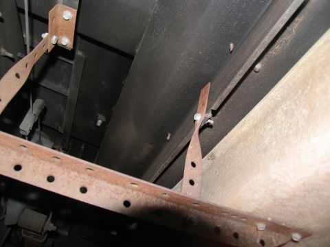 1995 Ford C-150 (Centurion Conversions) - Close-up view of the rusty metal brackets used to mount running boards to the underside of a vehicle.