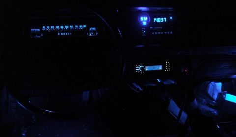 1991 Ford LTD Crown Victoria - The dashboard of a car at night, with glowing blue lights on the speedometer and radio display.