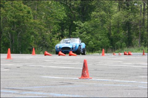2001 Mercury Grand Marquis - A blue convertible sports car drives through an autocross course with trees in the background.
