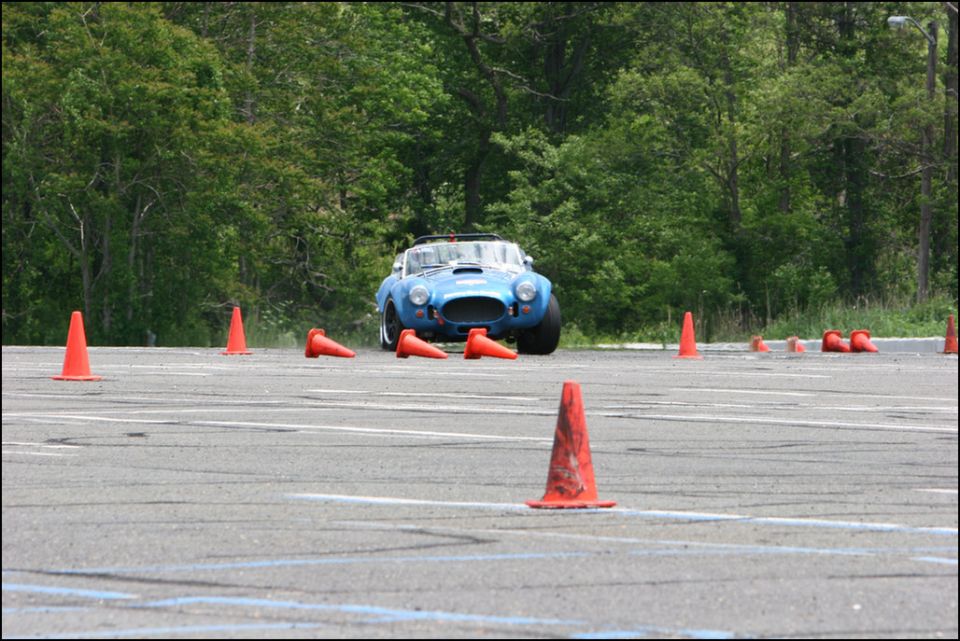 Blue convertible sports car navigating autocross course with orange cones