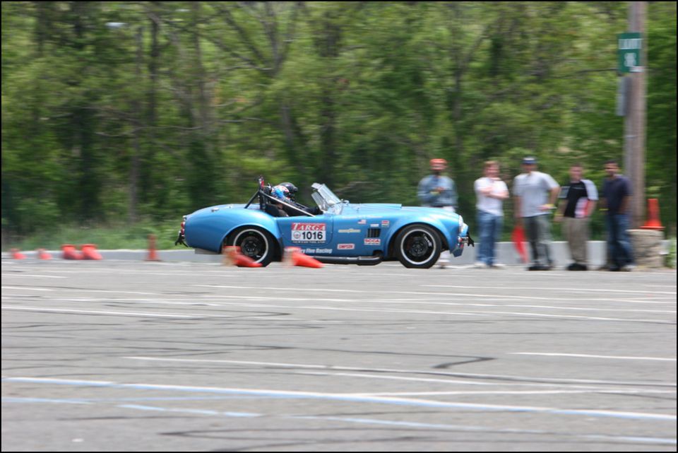 Blue convertible sports car with racing decals and number 1016 on the side, seen from the side at an autocross event