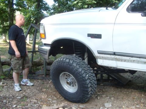 1992 Ford Bronco - A white 1992 Ford Bronco is shown with its large off-road tires and a man standing next to it.