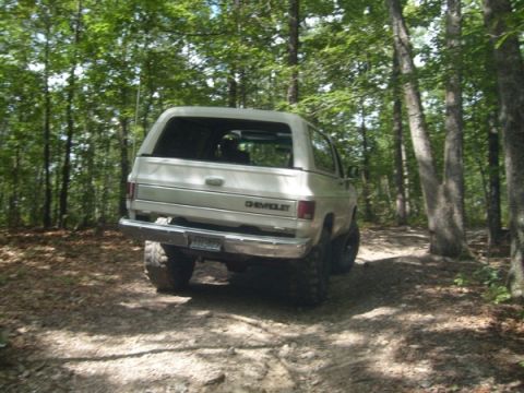 1992 Ford Bronco - A silver Chevrolet K5 Blazer navigates a wooded trail from a rear perspective.