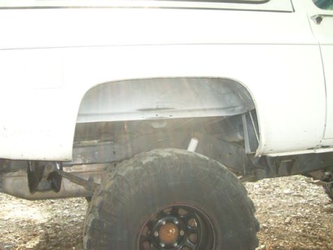 1992 Ford Bronco - The rear wheel well and tire of a white 1992 Ford Bronco are visible in this side view.