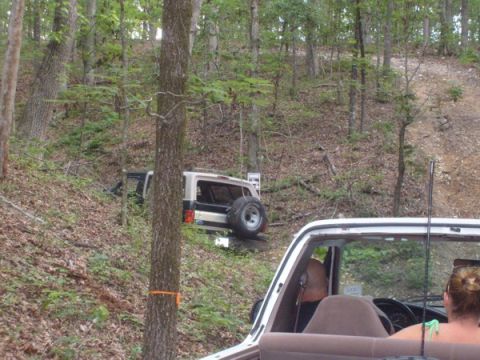 1992 Ford Bronco - A tan and white 1992 Ford Bronco is parked on a wooded hillside, with another vehicle in the foreground.