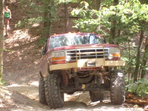 1992 Ford Bronco - Off-road modified 1992 Ford Bronco navigating a wooded trail.