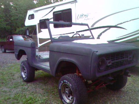 1974 Ford Bronco - This Ford Bronco is in a state of disassembly, parked next to an RV with another truck visible.