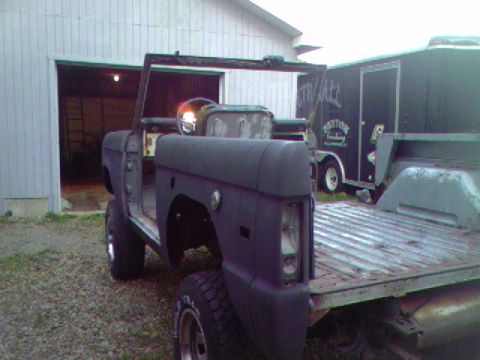 1974 Ford Bronco - A disassembled Ford Bronco sits in front of a garage, awaiting restoration.
