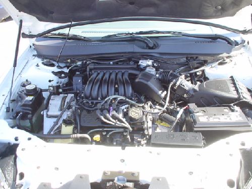 Engine bay with transverse V6 and black plastic intake, battery on right, hood up