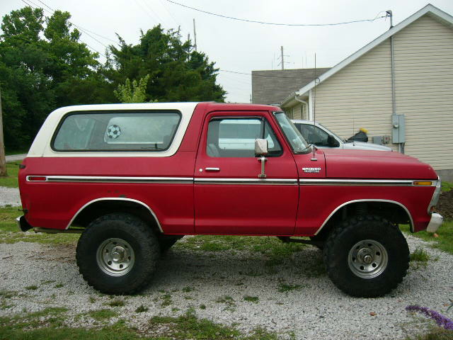 Red 1978 Ford Bronco with a white removable top, seen from the side