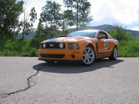 2007 Saleen S-302 - Orange Ford Mustang parked on asphalt with a scenic background of trees and hills.