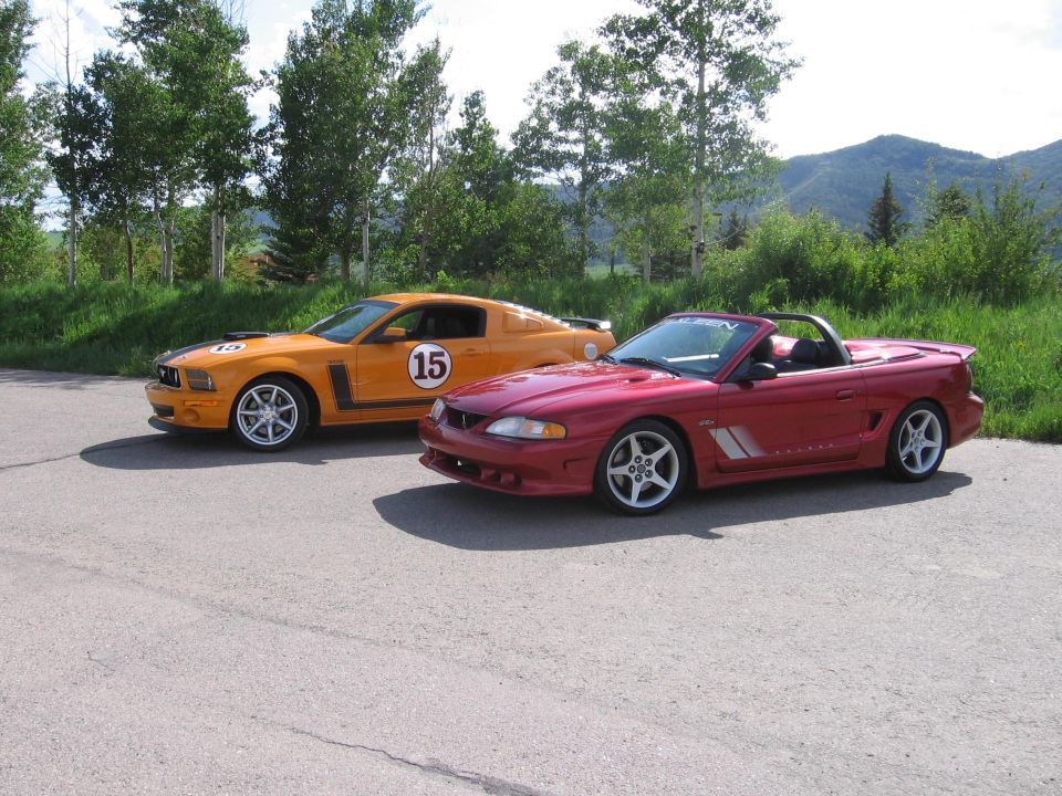 Orange Mustang with racing stripes and number 15, next to a red convertible Mustang