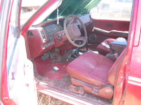 1973 Ford F-100 - The interior of a red truck shows maroon seats, dashboard, and door panels, with a view through the windshield.