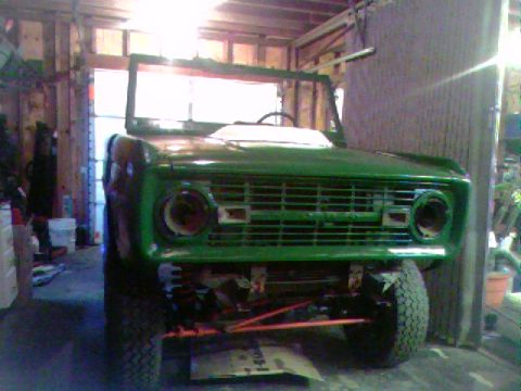 1974 Ford Bronco - Front view of a green 1974 Ford Bronco undergoing restoration in a garage.