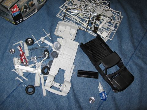 1974 Ford F-100 - Unassembled plastic model kit parts are spread out, a black truck body, chassis, wheels, and other components.