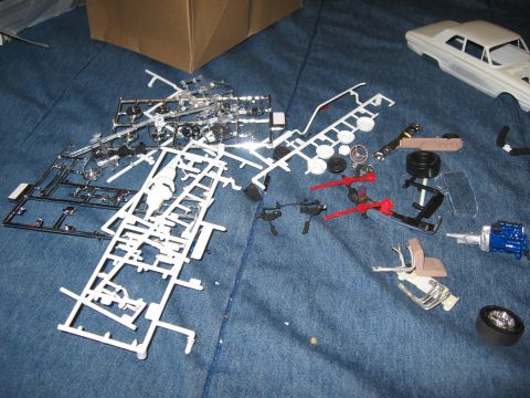 1974 Ford F-100 - Unassembled plastic model car parts are spread out, with a partially assembled model car body visible.