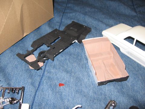 1974 Ford F-100 - Model car parts, including a chassis and interior, are laid out on a blue fabric surface.