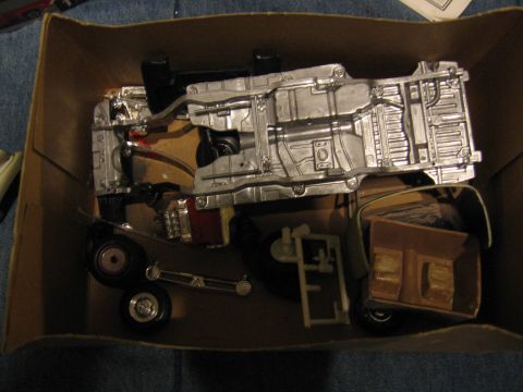 1974 Ford F-100 - Unassembled plastic model kit chassis and components are laid out inside a cardboard box.