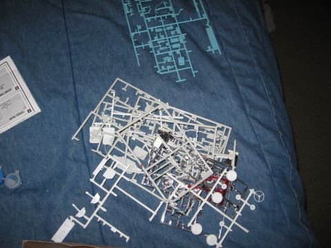 1974 Ford F-100 - Unassembled plastic model kit parts are spread out on a blue fabric surface next to instructions.