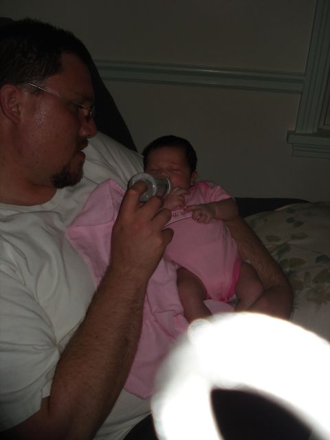 2000 Ford Crown Victoria - A father lovingly feeds his baby daughter from a bottle, capturing a tender moment of care and connection.
