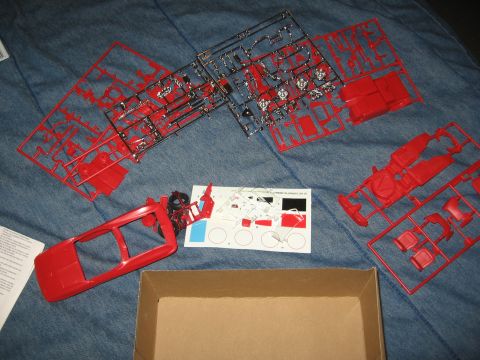 1974 Ford F-100 - Unassembled red plastic model car parts are laid out on a blue fabric surface next to a decal sheet.