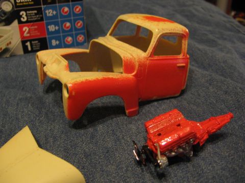 1974 Ford F-100 - Plastic model truck body and engine components are laid out on a blue fabric surface.