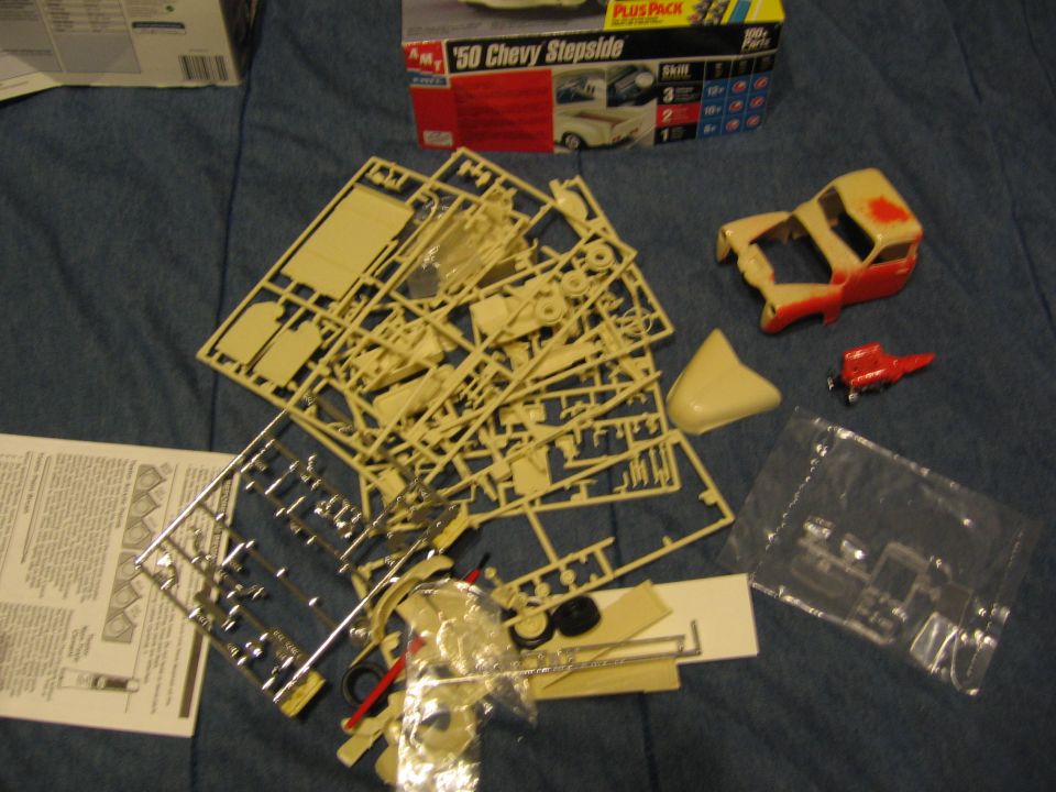 Model kit parts for a '50 Chevy Stepside, including sprues, a partially assembled body, and instructions