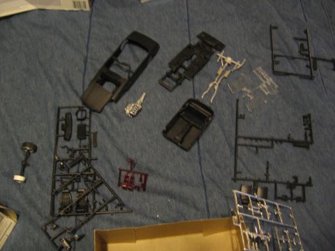 1974 Ford F-100 - Various unassembled plastic model kit parts are spread out, including a car body, chassis, engine, and wheels.