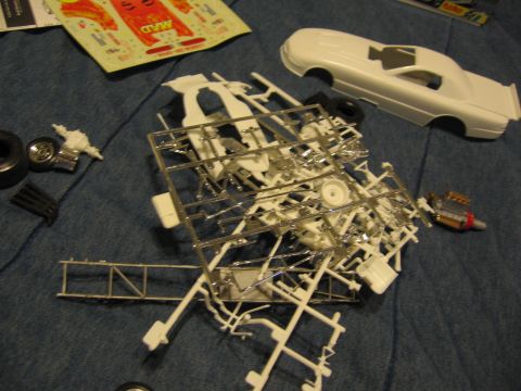 1974 Ford F-100 - Unassembled plastic model car parts and body laid out on a blue fabric surface.