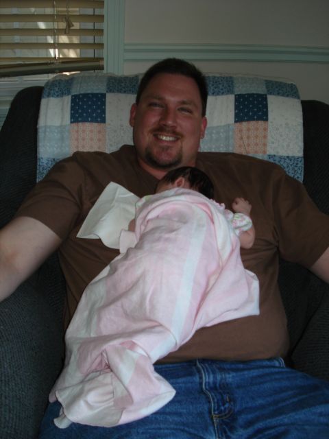 2000 Ford Crown Victoria - A man smiles while holding a baby wrapped in a pink and white blanket.