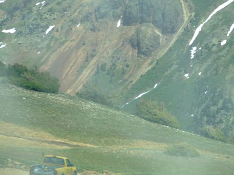 1987 Ford Bronco - A yellow 1987 Ford Bronco is parked on a grassy slope with a mountainous backdrop.