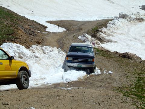 1987 Ford Bronco - A 1987 Ford Bronco navigates a snowy mountain pass, with another vehicle visible on the side of the road.