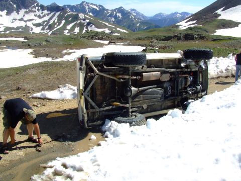1987 Ford Bronco - A 1987 Ford Bronco lies on its side after an apparent accident on a snowy mountain pass.