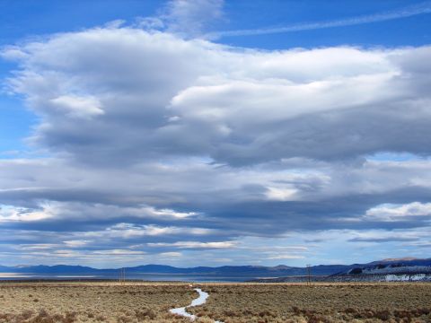 1996 Ford Bronco - Expansive sky with dramatic clouds above a barren landscape and a winding stream.