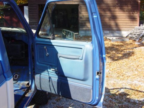 1985 Ford F-250 - Close-up of the interior door panel of a blue pickup truck, revealing its vintage design.